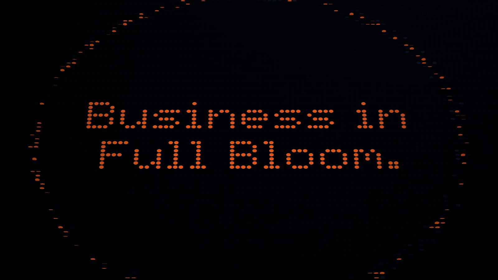 Seen from above, orange discs spell “Business in Full Bloom.” across the dark field, with a faint ring travelling outward.